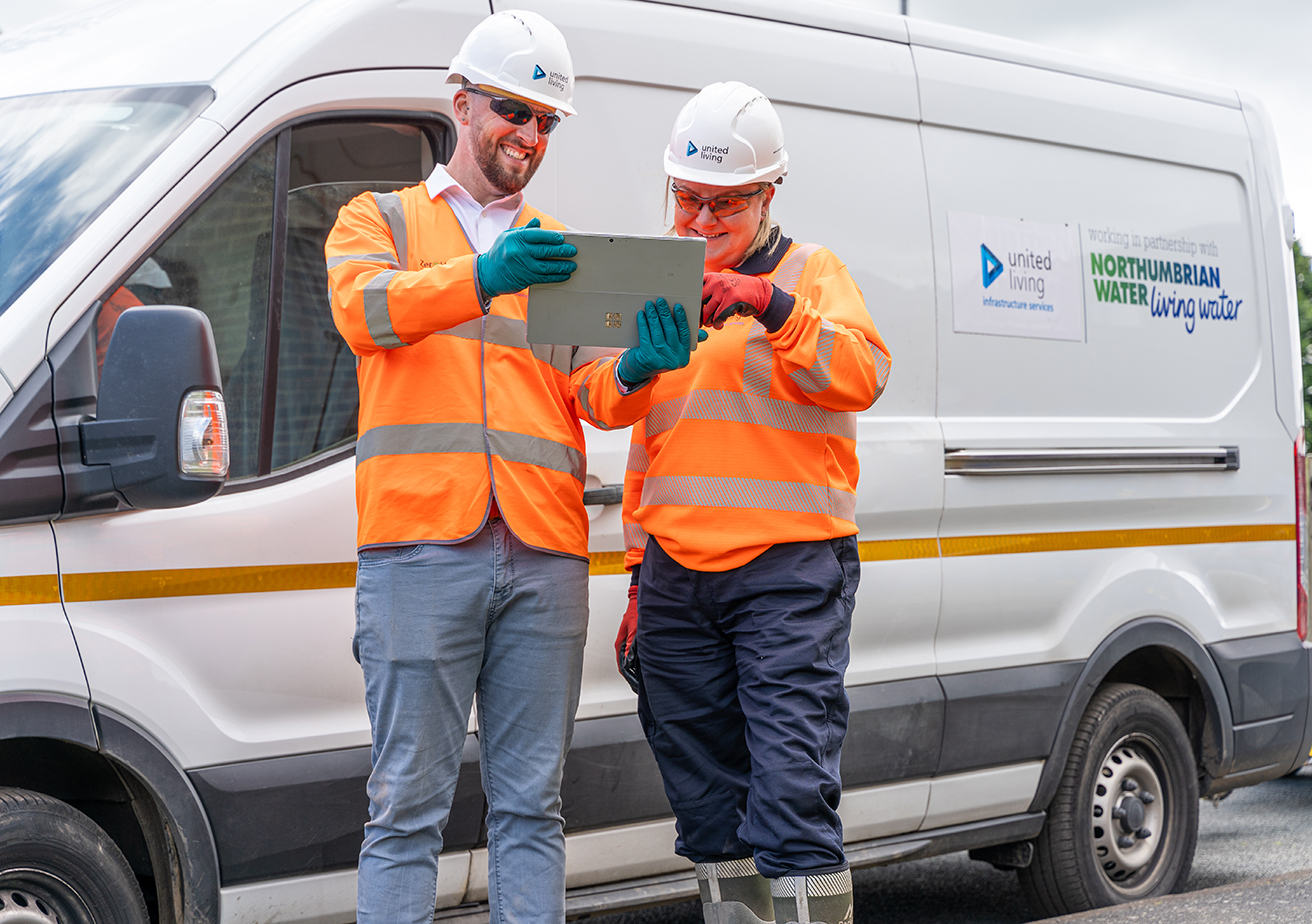 two construction workers reviewing notes in front of van