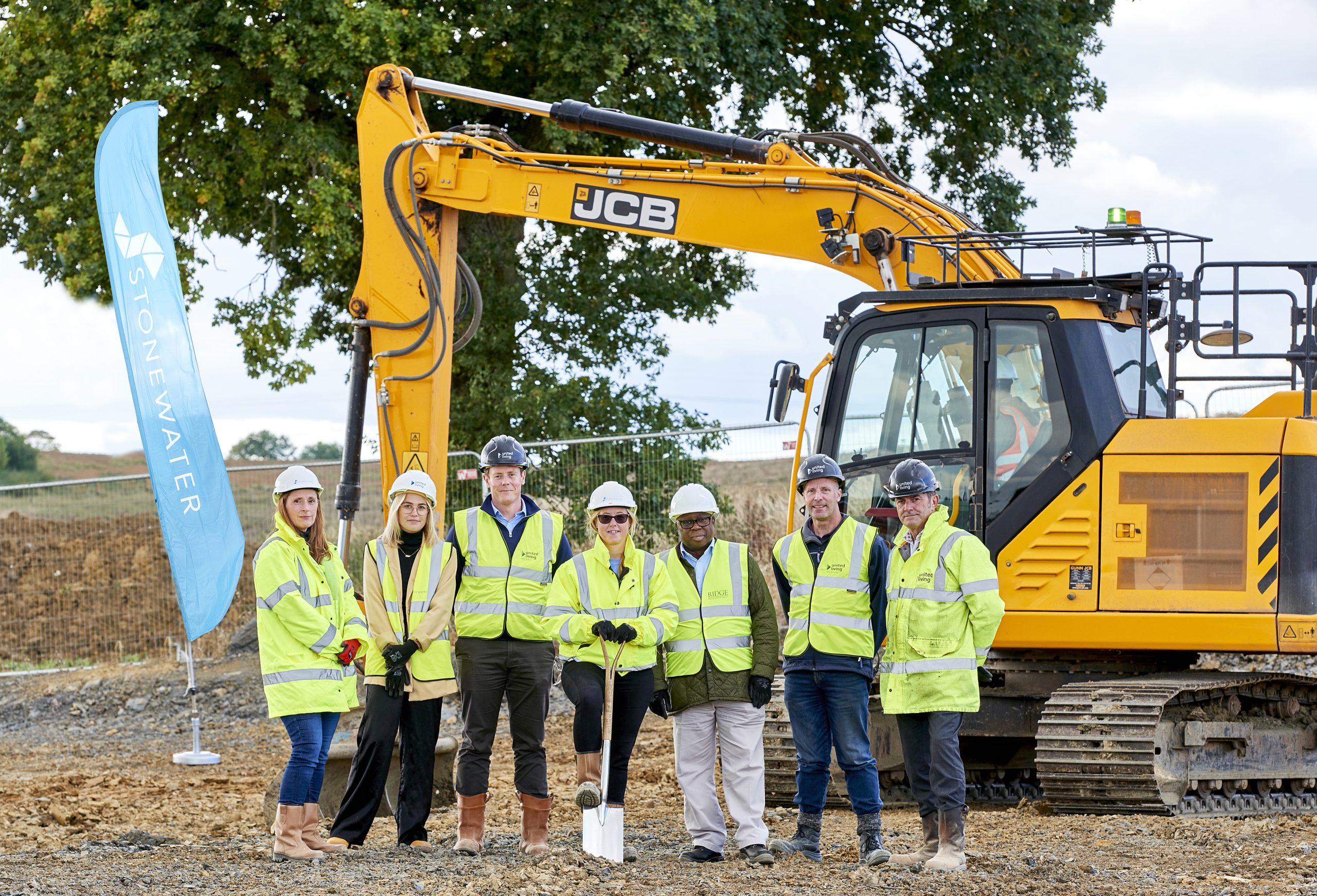 group of construction employees posing in front of a digger